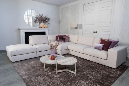 Beige hoekbank met grote hoek, gestyled met woonaccessoires in Burgundy.