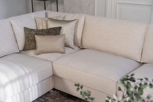 Lichte beige hoekbank met bruine woonaccessoires.