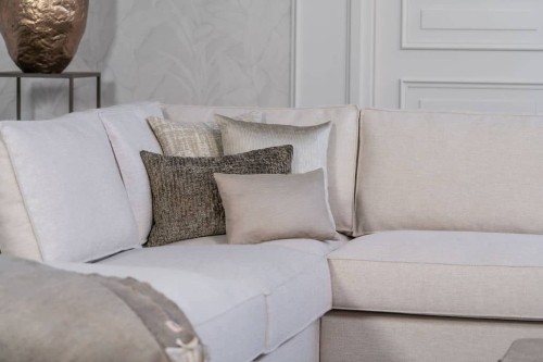 Lichte beige hoekbank met bruine woonaccessoires.