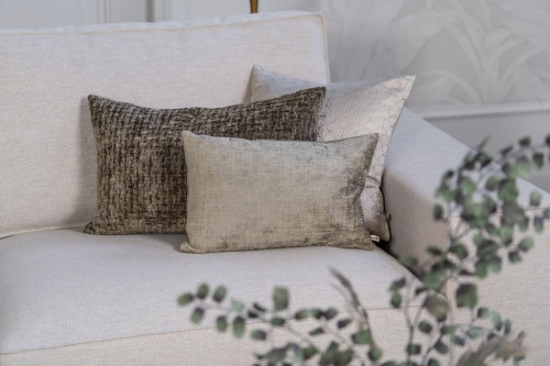 Lichte beige hoekbank met bruine woonaccessoires.