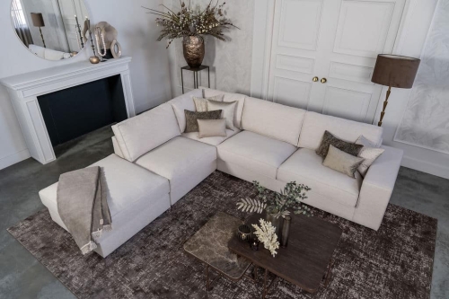Lichte beige hoekbank met bruine woonaccessoires.