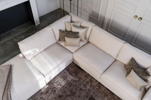 Lichte beige hoekbank met bruine woonaccessoires.