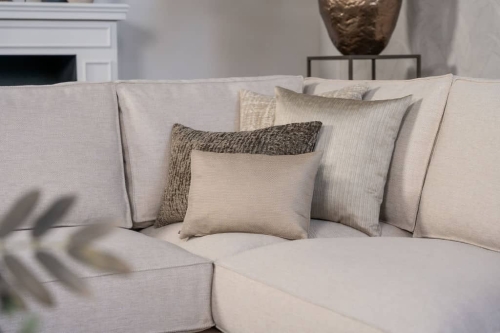 Lichte beige hoekbank met bruine woonaccessoires.
