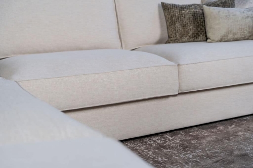 Lichte beige hoekbank met bruine woonaccessoires.