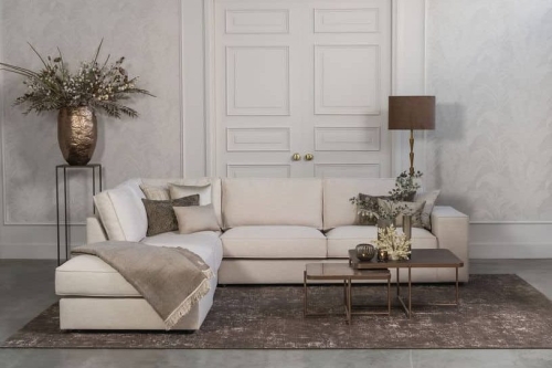 Lichte beige hoekbank met bruine woonaccessoires.