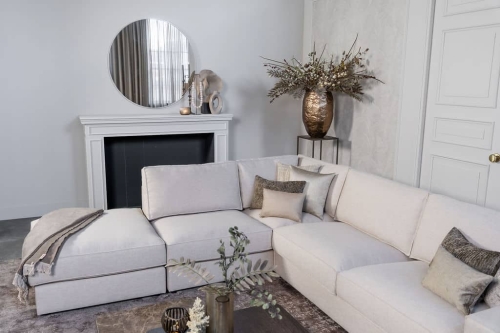 Lichte beige hoekbank met bruine woonaccessoires.