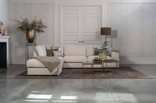 Lichte beige hoekbank met bruine woonaccessoires.